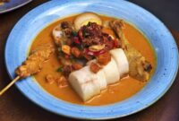 Semangkuk bubur pedas khas Singkawang yang kaya rempah dan sayuran segar, siap memanjakan lidah dengan cita rasa uniknya. Taburan teri dan kacang tanah renyah menambah tekstur yang menggugah selera.