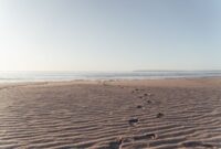 Jejak kaki di hamparan pasir pantai saat matahari terbenam menciptakan siluet indah yang seringkali menjadi simbol kedamaian dan kebebasan. Pemandangan ini mengingatkan kita akan keindahan alam yang tak ternilai dan pentingnya menjaganya.