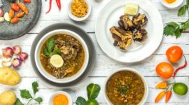 Semangkuk bubur pedas khas Indonesia dengan taburan bawang goreng dan pelengkap lainnya, siap menggoda selera dengan aroma rempah yang kuat dan cita rasa pedas yang khas. Hidangan ini menunjukkan kekayaan kuliner Nusantara yang berani bermain dengan spektrum rasa.