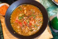 Semangkuk bubur pedas khas Indonesia yang hangat dan kaya rempah, dihiasi dengan irisan telur, bawang goreng, serta kerupuk renyah, siap menggugah selera dan menghadirkan sensasi pedas yang membakar. Hidangan ini memadukan tekstur lembut bubur dengan bumbu pedas yang intens, menciptakan pengalaman makan yang tak terlupakan.