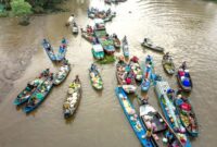 Pemandangan udara Sungai Kapuas yang membentang luas, memperlihatkan kekayaan alam dan aktivitas kehidupan di salah satu sungai terpanjang di Indonesia ini. Perahu-perahu tradisional nampak berlayar, menjadi bagian tak terpisahkan dari lanskap tersebut.