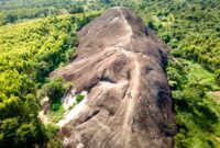 Pemandangan udara Bukit Kelam yang menjulang sendirian di tengah hamparan dataran hijau, memperlihatkan keagungan monolit alami ini dari sudut pandang yang menakjubkan. Bentuknya yang unik dan ukurannya yang masif menjadikan Bukit Kelam ikon alam yang tak terlupakan di Kalimantan Barat.