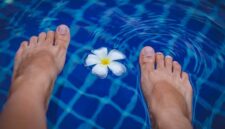 Seorang wanita sedang melakukan gerakan aqua aerobik di kolam renang, menikmati manfaat dari latihan air yang minim tekanan pada sendi namun tetap efektif membakar kalori. Aktivitas ini cocok untuk segala usia dan kondisi fisik, menawarkan cara menyegarkan untuk menjaga kebugaran tubuh.