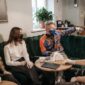 Suasana sebuah kedai kopi modern di tengah kota, menampilkan orang-orang yang sibuk dengan laptop atau berbincang santai, mencerminkan bagaimana kopi telah menjadi bagian tak terpisahkan dari gaya hidup perkotaan. Cahaya hangat dan desain interior yang nyaman menambah kesan akrab pada tempat ini.