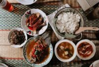 Semangkuk Bubur Pedas khas Kalimantan Barat yang mengepul hangat, siap memanjakan lidah dengan perpaduan rempah eksotis dan sensasi pedas yang membakar, dihiasi aneka sayuran segar serta taburan ikan teri dan kacang. Hidangan ini menunjukkan kekayaan warisan kuliner Nusantara yang patut dibanggakan.