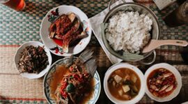 Semangkuk Bubur Pedas khas Kalimantan Barat yang mengepul hangat, siap memanjakan lidah dengan perpaduan rempah eksotis dan sensasi pedas yang membakar, dihiasi aneka sayuran segar serta taburan ikan teri dan kacang. Hidangan ini menunjukkan kekayaan warisan kuliner Nusantara yang patut dibanggakan.