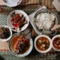 Semangkuk Bubur Pedas khas Kalimantan Barat yang mengepul hangat, siap memanjakan lidah dengan perpaduan rempah eksotis dan sensasi pedas yang membakar, dihiasi aneka sayuran segar serta taburan ikan teri dan kacang. Hidangan ini menunjukkan kekayaan warisan kuliner Nusantara yang patut dibanggakan.