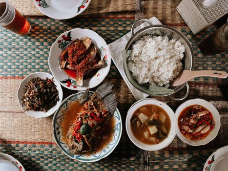 Semangkuk Bubur Pedas khas Kalimantan Barat yang mengepul hangat, siap memanjakan lidah dengan perpaduan rempah eksotis dan sensasi pedas yang membakar, dihiasi aneka sayuran segar serta taburan ikan teri dan kacang. Hidangan ini menunjukkan kekayaan warisan kuliner Nusantara yang patut dibanggakan.