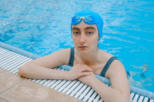 Seorang wanita melakukan gerakan aqua aerobic dengan riang di dalam kolam renang, menunjukkan bagaimana olahraga air bisa menjadi aktivitas kebugaran yang menyenangkan dan menyegarkan. Latihan di dalam air mengurangi beban pada sendi sekaligus memberikan resistensi alami untuk melatih otot secara efektif.