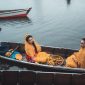 Perahu tradisional melintasi aliran Sungai Kapuas yang tenang, dikelilingi rimbunnya hutan hujan tropis Kalimantan, menunjukkan harmoni antara manusia dan alam.