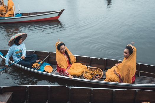 Perahu tradisional melintasi aliran Sungai Kapuas yang tenang, dikelilingi rimbunnya hutan hujan tropis Kalimantan, menunjukkan harmoni antara manusia dan alam.