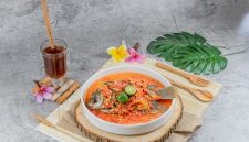 Semangkuk bubur pedas khas Singkawang dengan taburan kacang tanah, ikan teri, dan beragam sayuran segar yang siap memanjakan lidah Anda dengan cita rasa unik dan pedas yang menghangatkan. Hidangan ini merupakan perpaduan sempurna antara kekayaan rempah dan tekstur yang beragam.