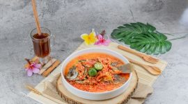Semangkuk bubur pedas khas Singkawang dengan taburan kacang tanah, ikan teri, dan beragam sayuran segar yang siap memanjakan lidah Anda dengan cita rasa unik dan pedas yang menghangatkan. Hidangan ini merupakan perpaduan sempurna antara kekayaan rempah dan tekstur yang beragam.