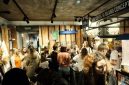 Suasana hangat di sebuah kedai kopi modern, tempat para pengunjung berkumpul untuk bekerja, berdiskusi, atau sekadar menikmati secangkir kopi racikan barista. Kopi telah menjadi medium esensial yang mempertemukan berbagai individu dan ide.