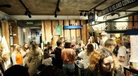 Suasana hangat di sebuah kedai kopi modern, tempat para pengunjung berkumpul untuk bekerja, berdiskusi, atau sekadar menikmati secangkir kopi racikan barista. Kopi telah menjadi medium esensial yang mempertemukan berbagai individu dan ide.